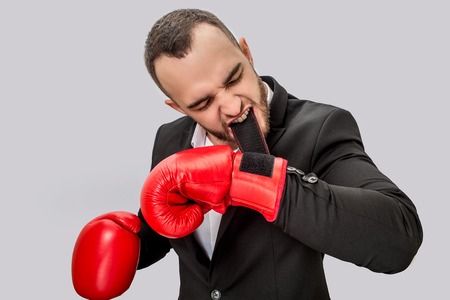 Serious and angry young man getting ready to fight. He holds clasp in mouth. Guy is concentrated. He...