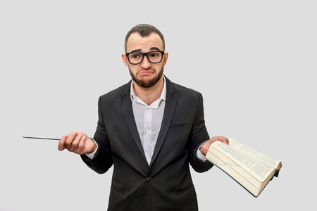 Frustrated and unhappy young man in suit looks straight through glasses. He hold pen and book in hands. Isolated on white background.の写真素材