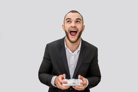 Happy young man stand and look up. He wears suit. Guy holds remote control. He is happy. Isolated on...