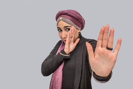 Afraid young arabian woman look at camerea. She try to cver her face with hands. She is scared....