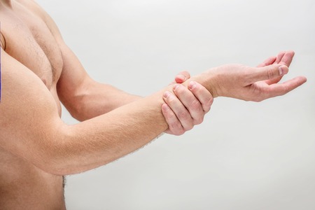 Side shot of young man hold hand on wrist. He is shirtless. Isolated on white background.の写真素材