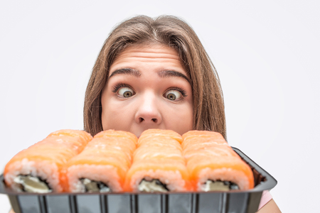 Excited young woman look at set of rolls. She is amazed. Isolated on white background.の写真素材