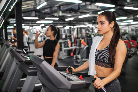 Serious and calm young woman look forward. She stand on running track and hold hands on it. Asian...