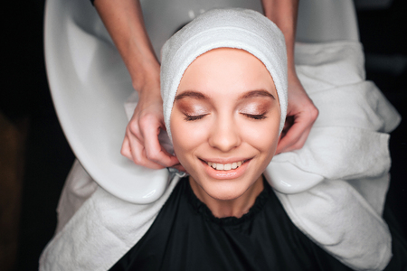 Top view of smiling beautiful young woman satisfied after professional washing and treating hair in beauty salon. Effective hair careの写真素材