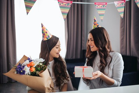 Beautiful brunette caucasian mother and daughter prepare celebration together in room.の写真素材