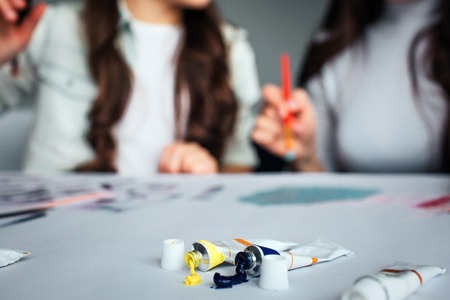Beautiful brunette caucasian mother and daughter paint together in room.の写真素材
