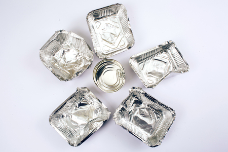 Plastic pollution concept. Metal can in the center of foil containers for food on white background, top view. Single-use plastic. New rules to reduce plastic waste, EU directive. We can no longer pollute our planetの写真素材
