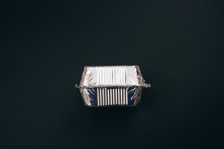 Stop plastic pollution. Foil silver container for food on dark background, top view. No to...