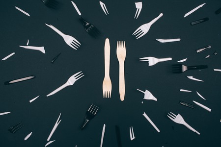 Plastic free. Zero waste concept. Eco-friendly unbroken forks in the center of single-use broken white and black forks on dark background. Choose single-use plastic or natural recyclable product. Top viewの写真素材