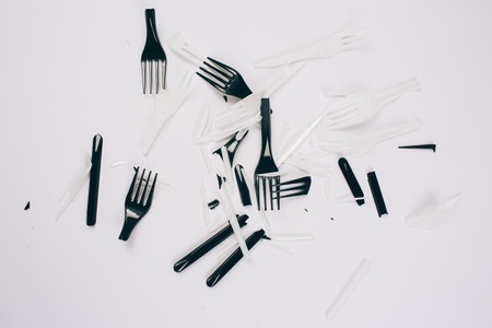 Plastic pollution concept. No to plastic. Broken single-use white and black forks on dark...