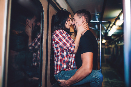 Young man and woman use underground. Couple in subway. Passionate kiss. Young man hold woman on hands. Close to each other. Underground carriage.の写真素材