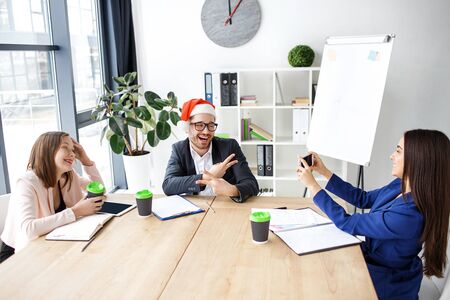 Workers in office. Cheerful attractive people celebrating new year or Christmas. Brunette taking picture of man and smile. Happy together. Holidays at work.の写真素材