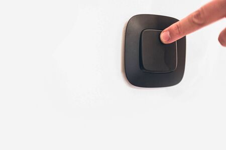 Turning off or turning light switch on wall with finger. Caucasian hand. Contrast picture. White...