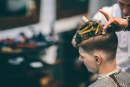 Hairdresser makes hairstyle a man with a clip on the head in a hairdressing salon