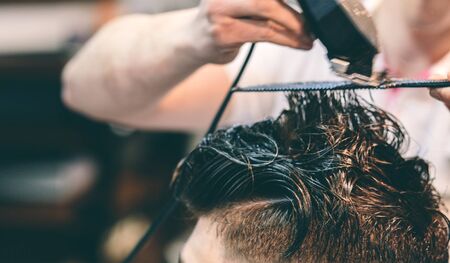 Hairdresser makes hairstyle a man with a clip on the head in a hairdressing salon