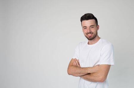 Young man isolated over background. Confident attractive guy hold hands crossed and pose on camera....