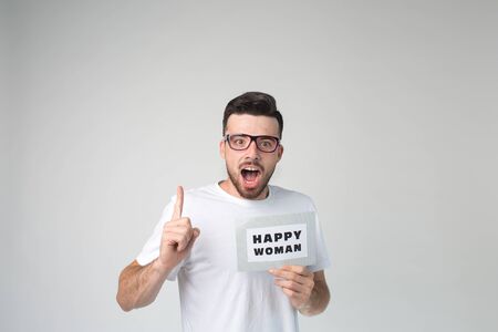 Young man isolated over background. Emotional guy teaches about woman happiness. Hold big thumb up. Guy look straight through glasses. Alone in studio.の写真素材