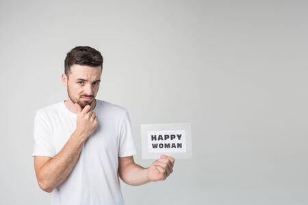 Young man isolated over background. Dissapointed scary guy hold piece of paper in hand and look on...