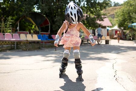 Picture of young roller skater outside skating alone. Professional baby in skating equipment have fun riding. Sunshine and summertime.の写真素材