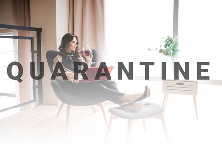 Young businesswoman work at home. Sitting in chair and drink red wine from glass. Remote work. Red...