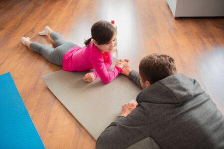 father and daughter are training at home. Workout in the apartment. Sports at home. Compete in arm...