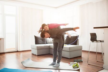 father and daughter are training at home. Workout in the apartment. Sports at home. Daughter climbed...