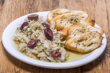 shredded cod with olive oil and olives served with bread toast on wooden background.の写真素材