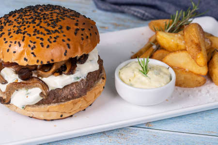 Close up delicious burger with sauce and shitake mushroom served with rustic potatoes.の写真素材