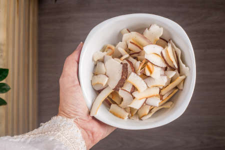 Hand with bowl of coconut chips