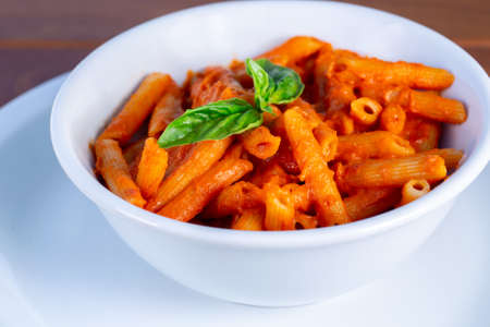 
penne in tomato sauce in white bowl on wooden background.の写真素材