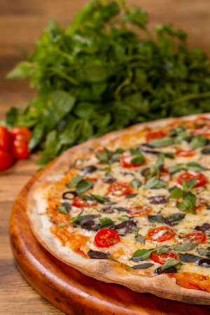 
Cherry tomato pizza, black olive and basil on wooden background.の写真素材