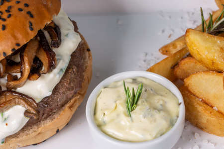 Close up delicious burger with sauce and shitake mushroom served with rustic potatoes.の写真素材