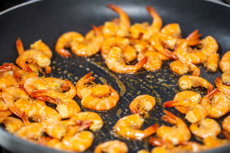 Process of frying shrimp with garlic in olive oil in the black pan. step by step cooking.の写真素材