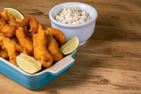 View of crispy fish, fish fingers or strips served with tartar sauce and lemon slices. Kid meal, appetizer or snack food made using a whitefishの写真素材