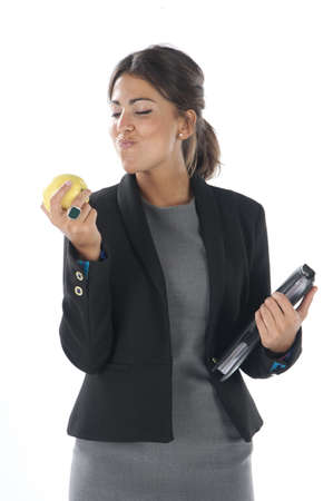Waist up, young business executive woman, on white, biting an apple.の写真素材