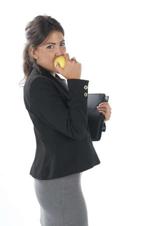 Waist up, young business executive woman, on white, biting an apple.の写真素材