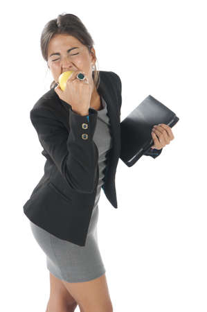 Waist up, healthy young business executive woman, on white, eating an apple.の写真素材