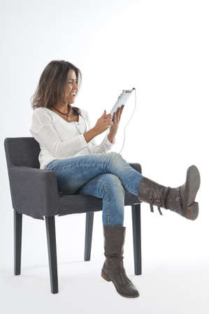 Happy young girl wearing casual clothing, on white, sitting on sofa holding tablet PC.の写真素材