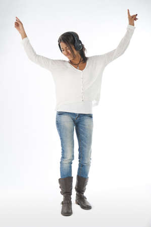 Full length portrait of young girl, on white, wearing casual clothing, enjoying music with hands up and head phones の写真素材