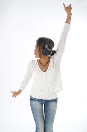 Three quarter length portrait of young girl with casual clothing, on white,  enjoying music with headphones and hands up.の写真素材