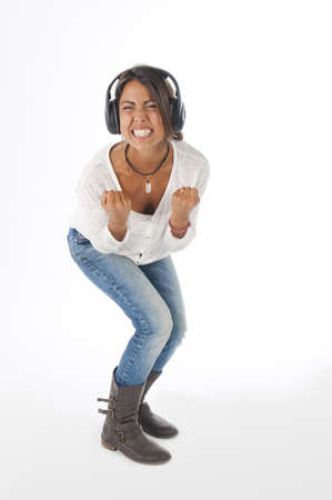 Happy young female adult with headphones, enjoying singing with open mouth and dancing, while listening to music の写真素材