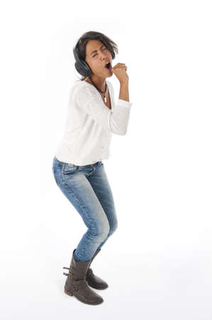 Happy young female adult with headphones, enjoying simulating singing with microphone while dancing  listening to music.の写真素材