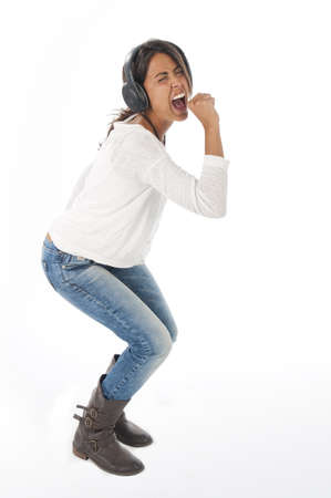 Happy young female adult with headphones, enjoying simulating singing with microphone while dancing  listening to music.の写真素材