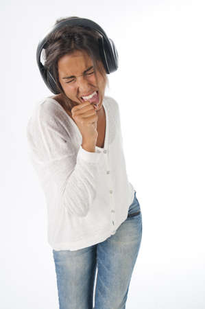Three quarters length portrait of young woman with casual clothing and headphones, on white background,  enjoying music singing and dancing の写真素材