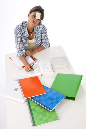 High Angle view of young female tired student in front of table with books and notebooks の写真素材
