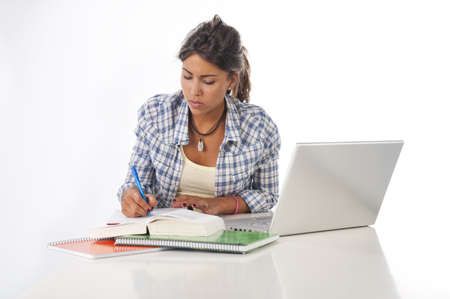 Young female student concentrated studying with laptop, books and notebooks on table.の写真素材