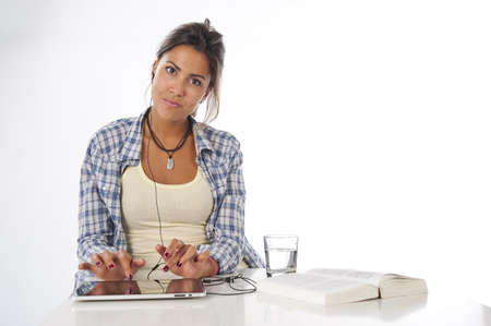 Portrait of young female student working with tablet PC, with book on table looking at camera.の写真素材