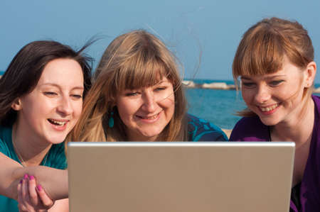 Three girls with a laptop on a beachの写真素材