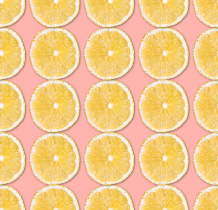 Fresh yellow lemon slices seamless pattern. Close up of citrus fruit slices on pastel pink background. Studio photography.の写真素材