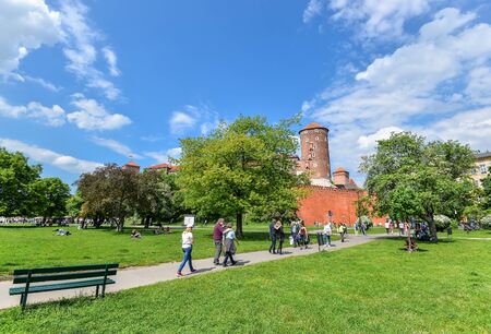 Krakow, Poland - May 20, 2019: Vew on surrounding wall and tower of Wawel Castle, spring park and walking touristsのeditorial素材
